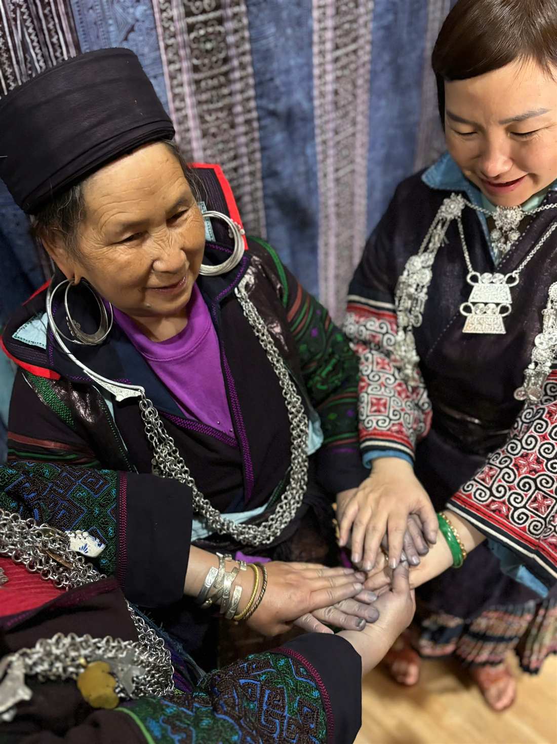 Hands joined, wearing Hmong silver jewelry
