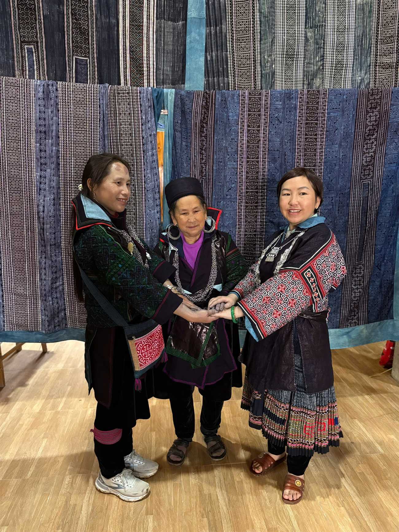 Mother Ly Thi Khu (center) joining hands with two other Hmong women in traditional costume, Lao Chai